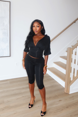 Woman wearing Demuluxe Vale Capri Set, a plunge-neckline two-piece with cinched waist and fitted capri pants