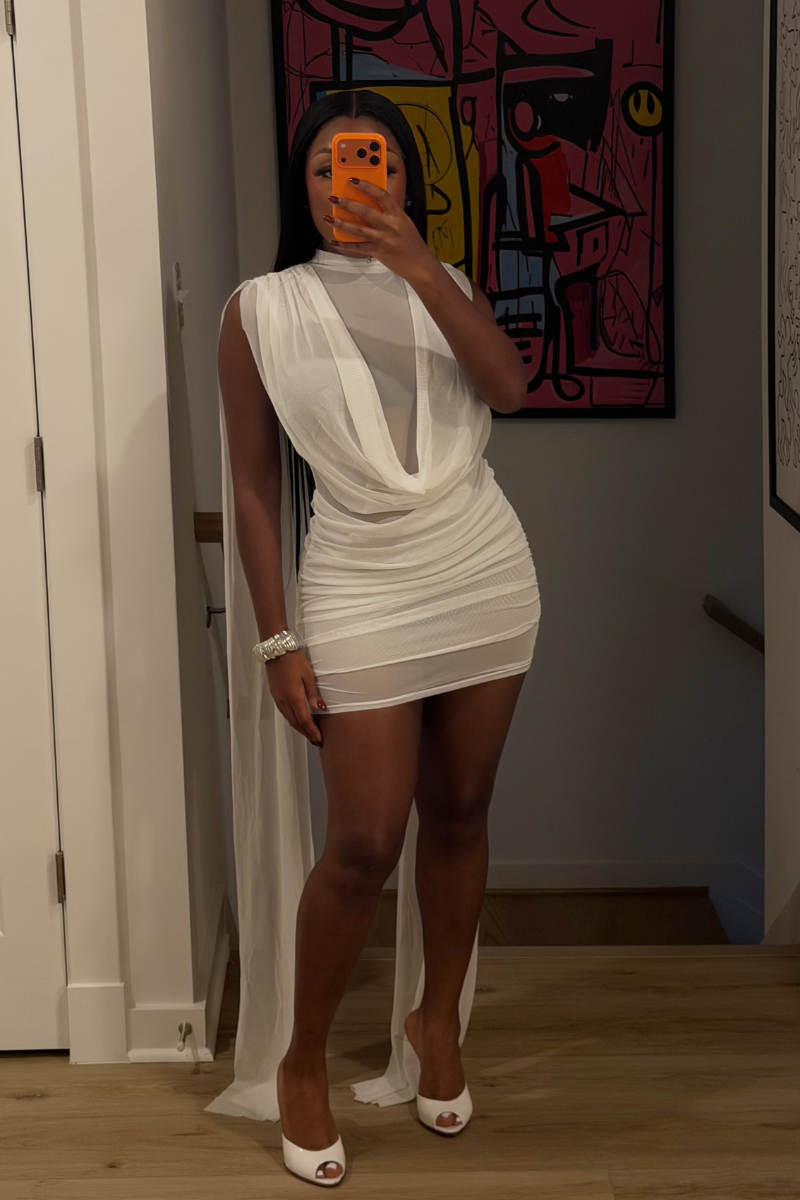 Woman wearing Demuluxe Yara Mini Dress, a sheer mesh mini dress with draped cowl front and long flowing train