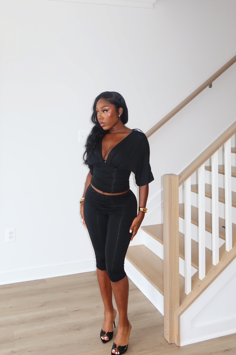 Woman wearing Demuluxe Vale Capri Set, a plunge-neckline two-piece with cinched waist and fitted capri pants
