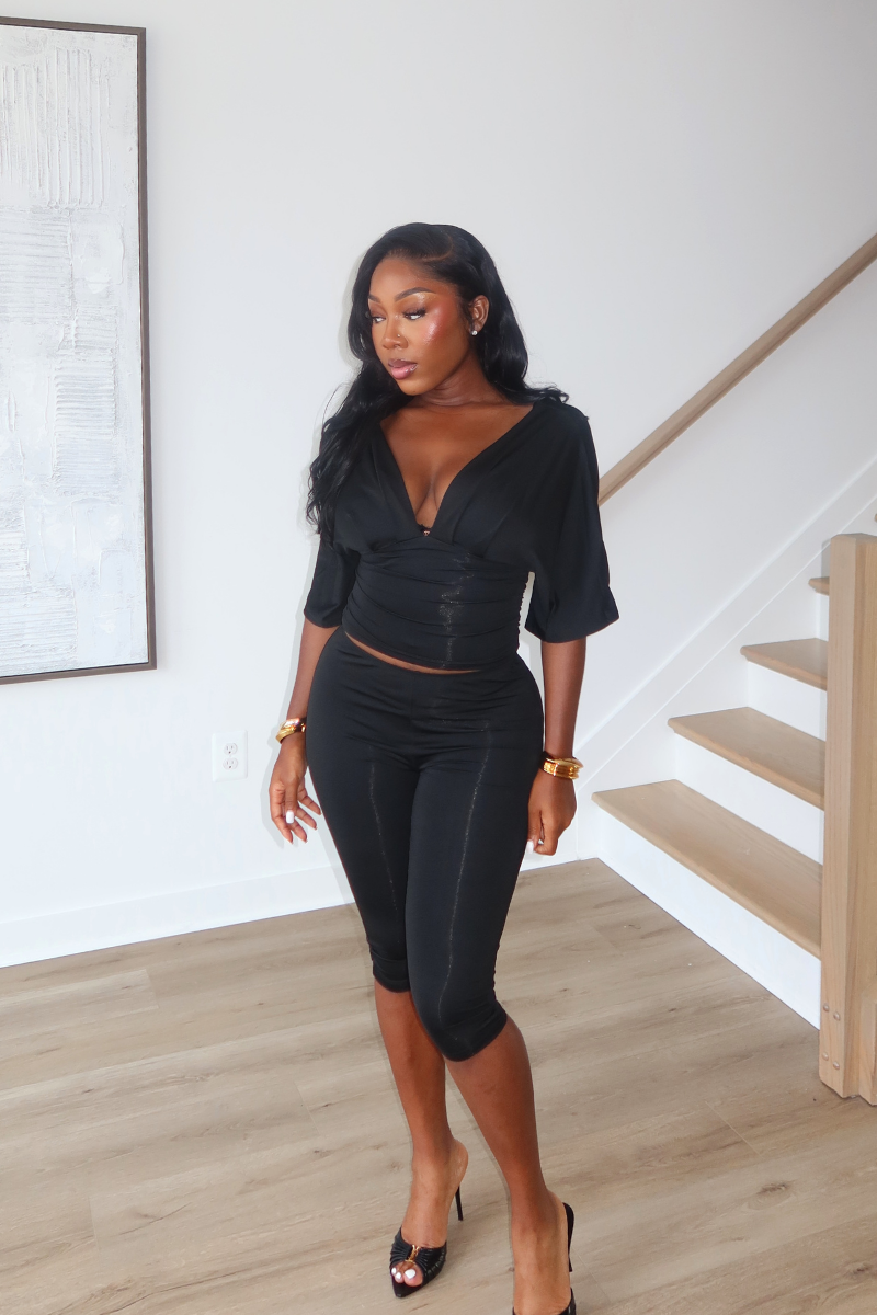 Woman wearing Demuluxe Vale Capri Set, a plunge-neckline two-piece with cinched waist and fitted capri pants