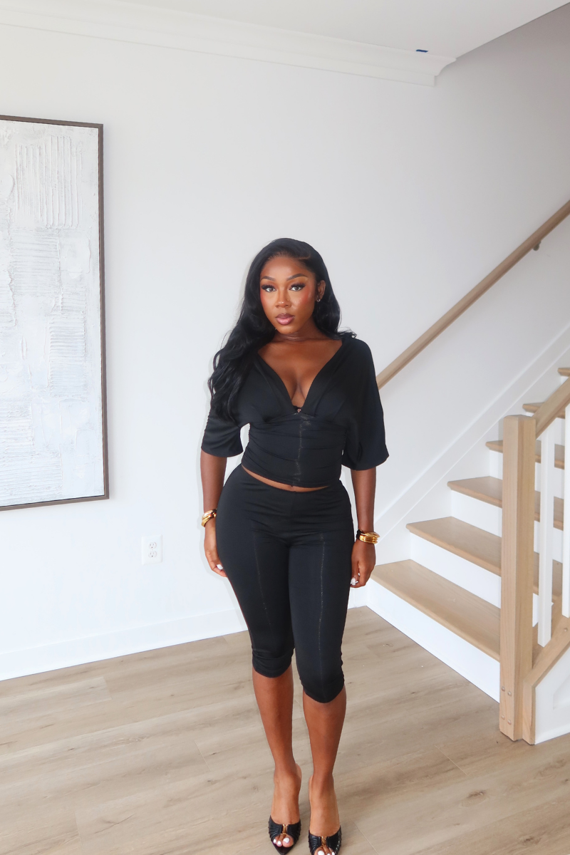 Woman wearing Demuluxe Vale Capri Set, a plunge-neckline two-piece with cinched waist and fitted capri pants