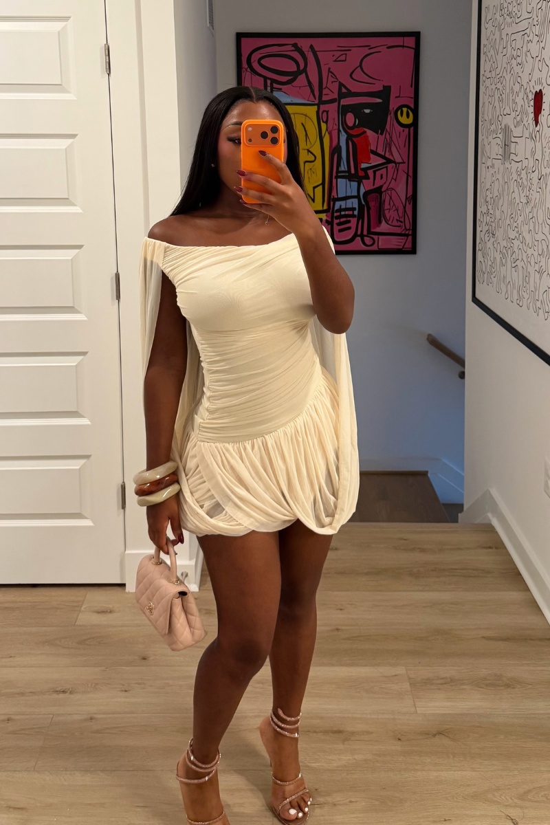 Woman wearing Demuluxe Brielle Mini Dress, a white draped mini dress with cape sleeves