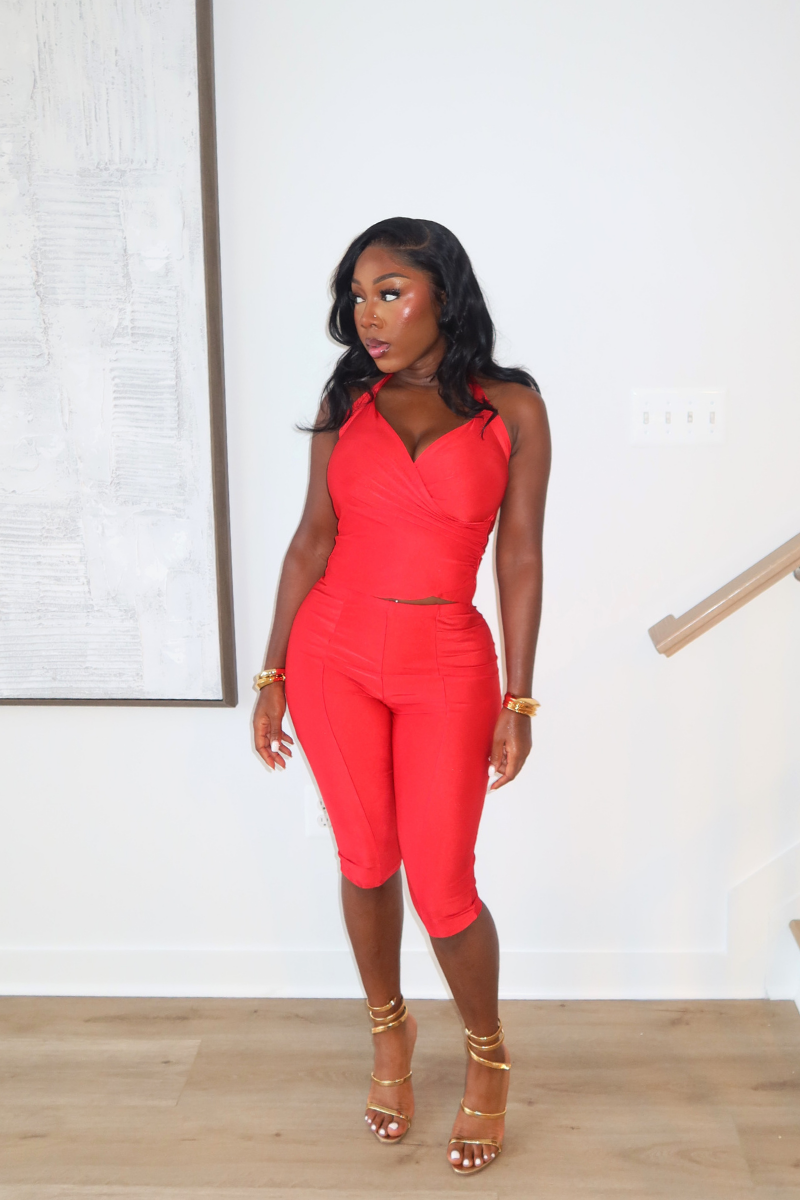 Woman wearing Demuluxe Reya Halter Capri Set, a red crossover halter top with matching high-waisted capri pants