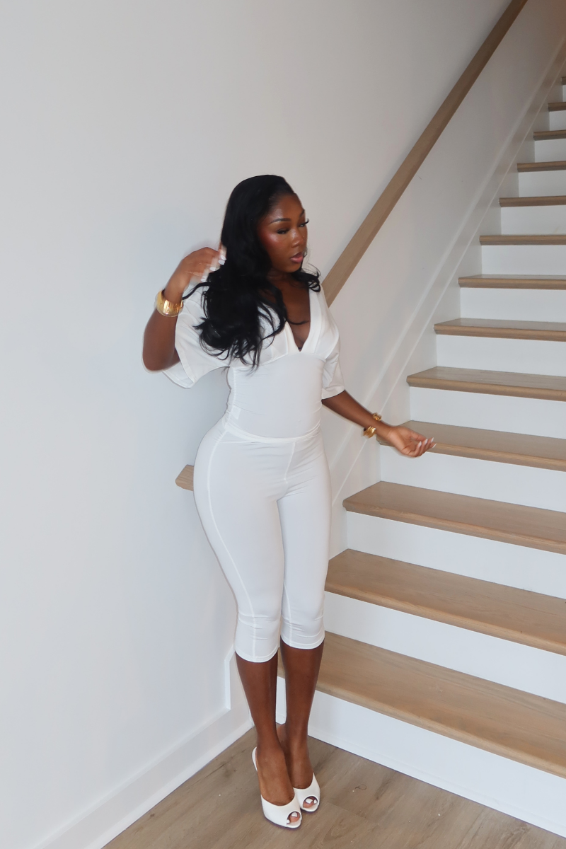 Woman wearing Demuluxe Vale Capri Set, a plunge-neckline two-piece with cinched waist and fitted capri pants
