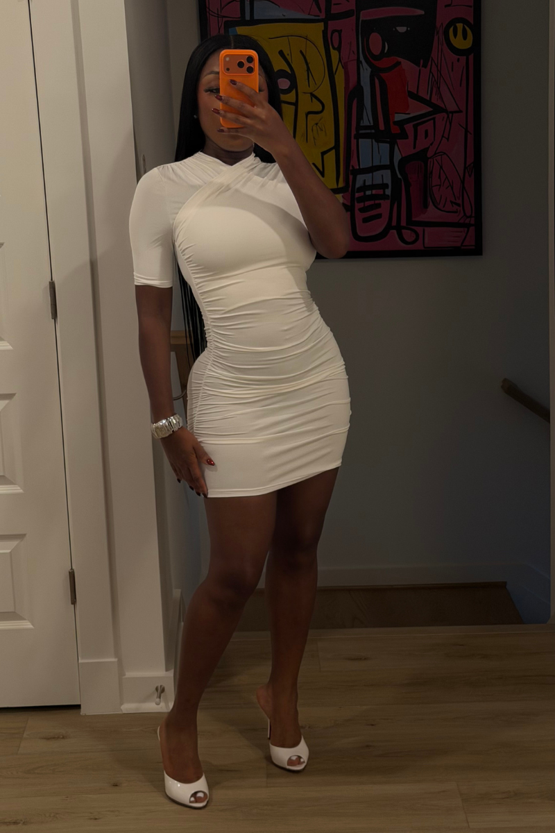 Woman wearing Demuluxe Ashley Dress, a white ruched mini dress with crisscross neckline and short sleeves