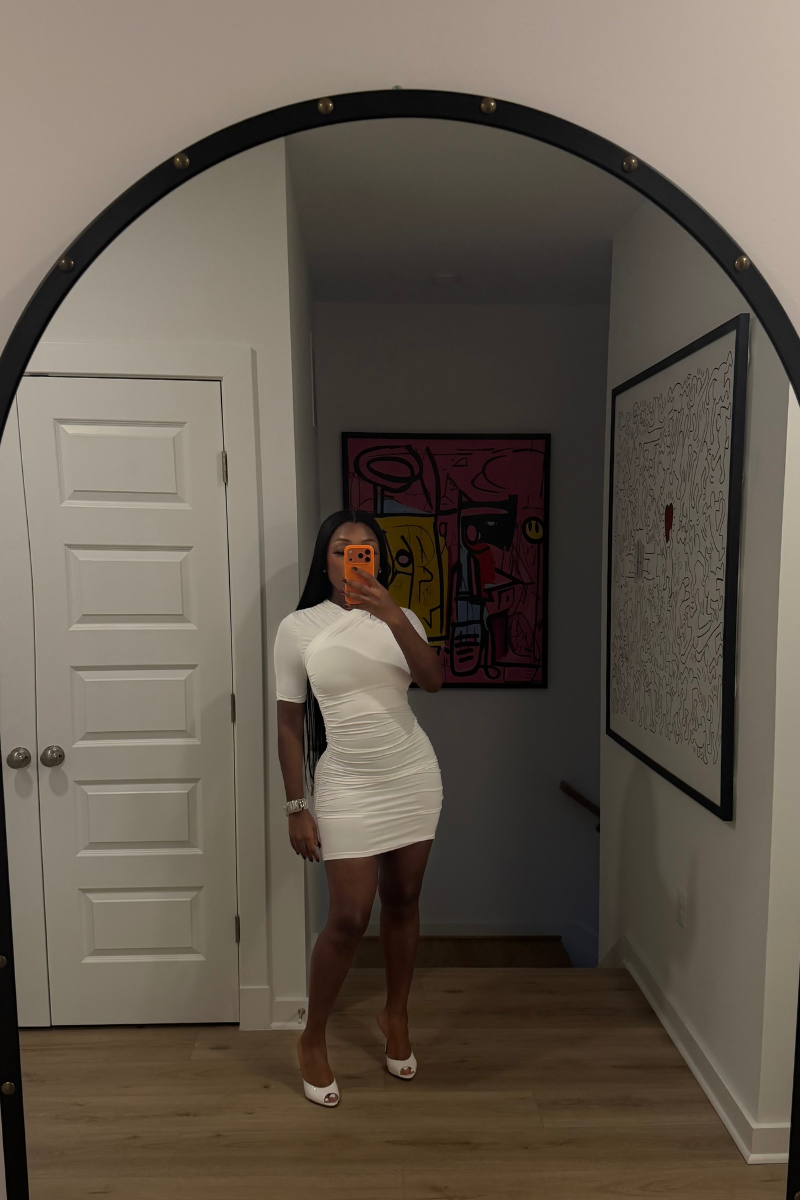 Woman wearing Demuluxe Ashley Dress, a white ruched mini dress with crisscross neckline and short sleeves