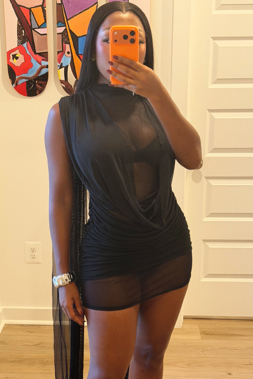 Woman wearing Demuluxe Yara Mini Dress, a sheer mesh mini dress with draped cowl front and long flowing train