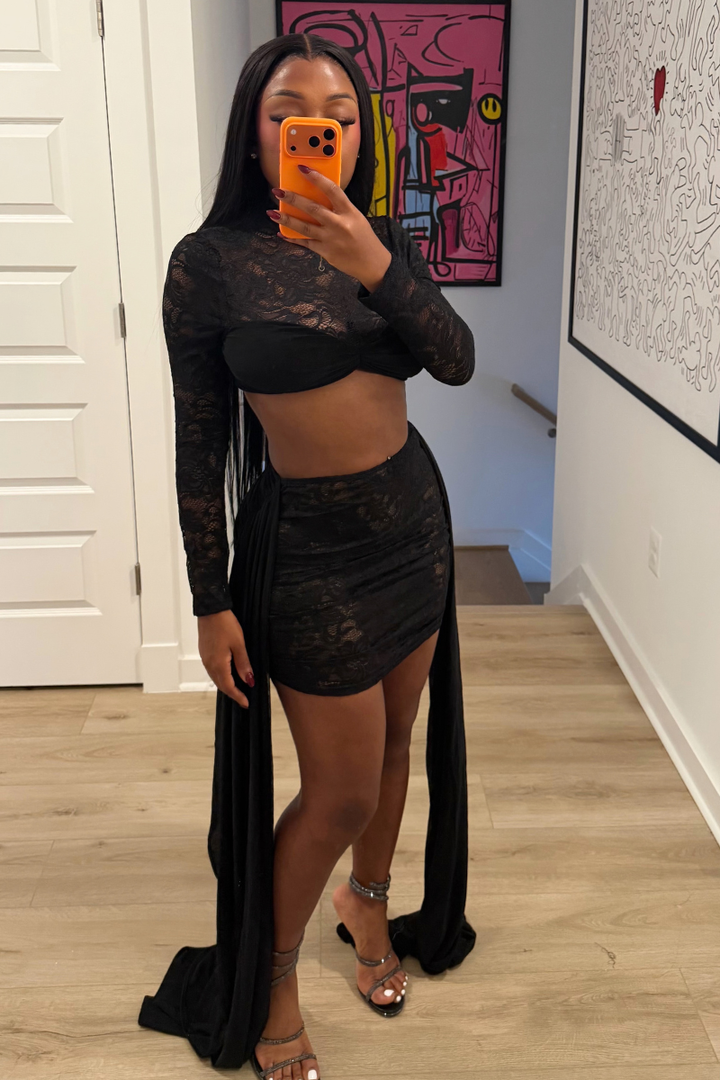 Woman wearing Demuluxe Odessa Lace Set, a black sheer lace crop top and mini skirt with draped tails