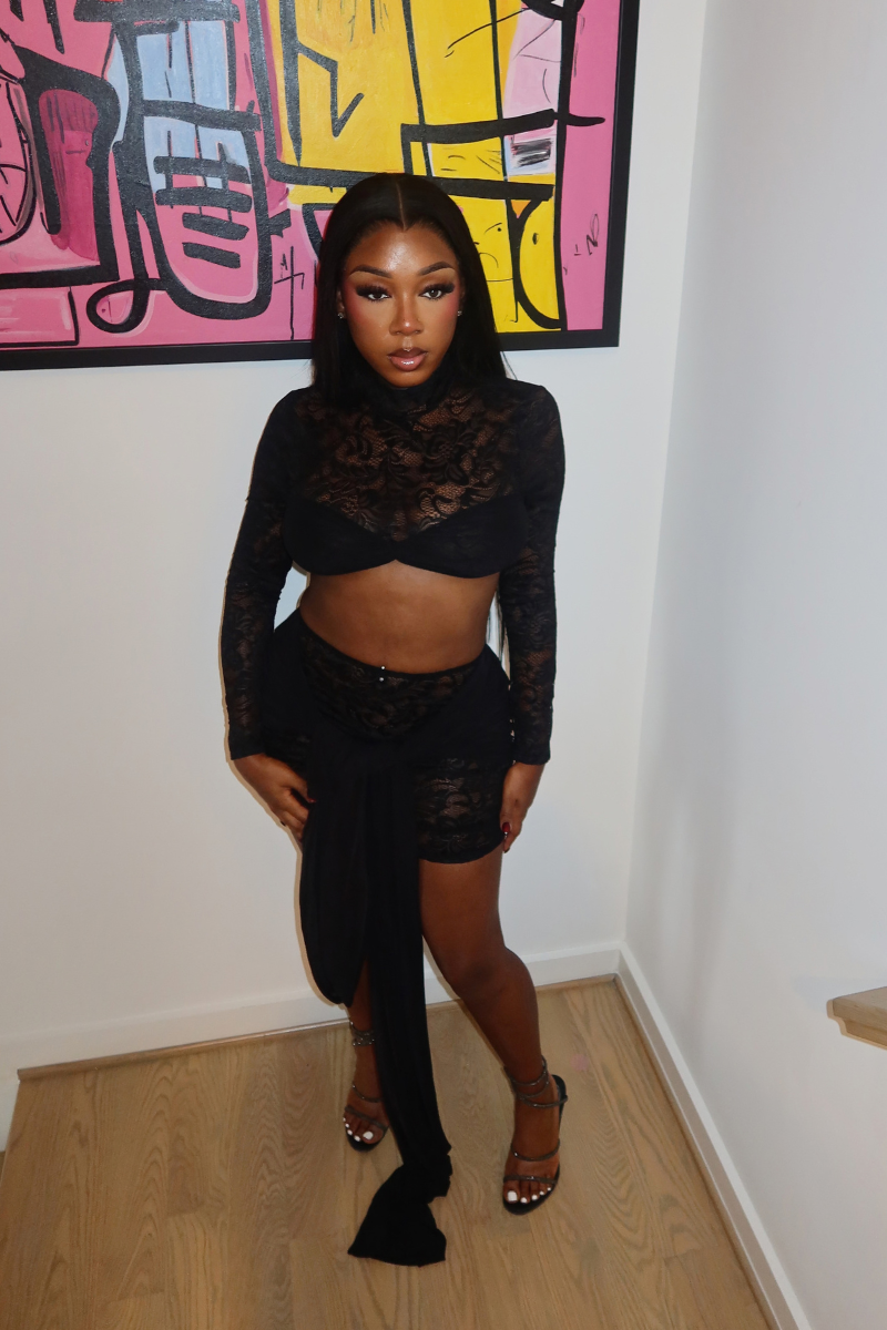 Woman wearing Demuluxe Odessa Lace Set, a black sheer lace crop top and mini skirt with draped tails