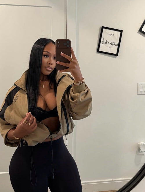 Woman wearing Demuluxe Remy Bomber Jacket, a cropped tan utility bomber with black paneling and drawstring hem 