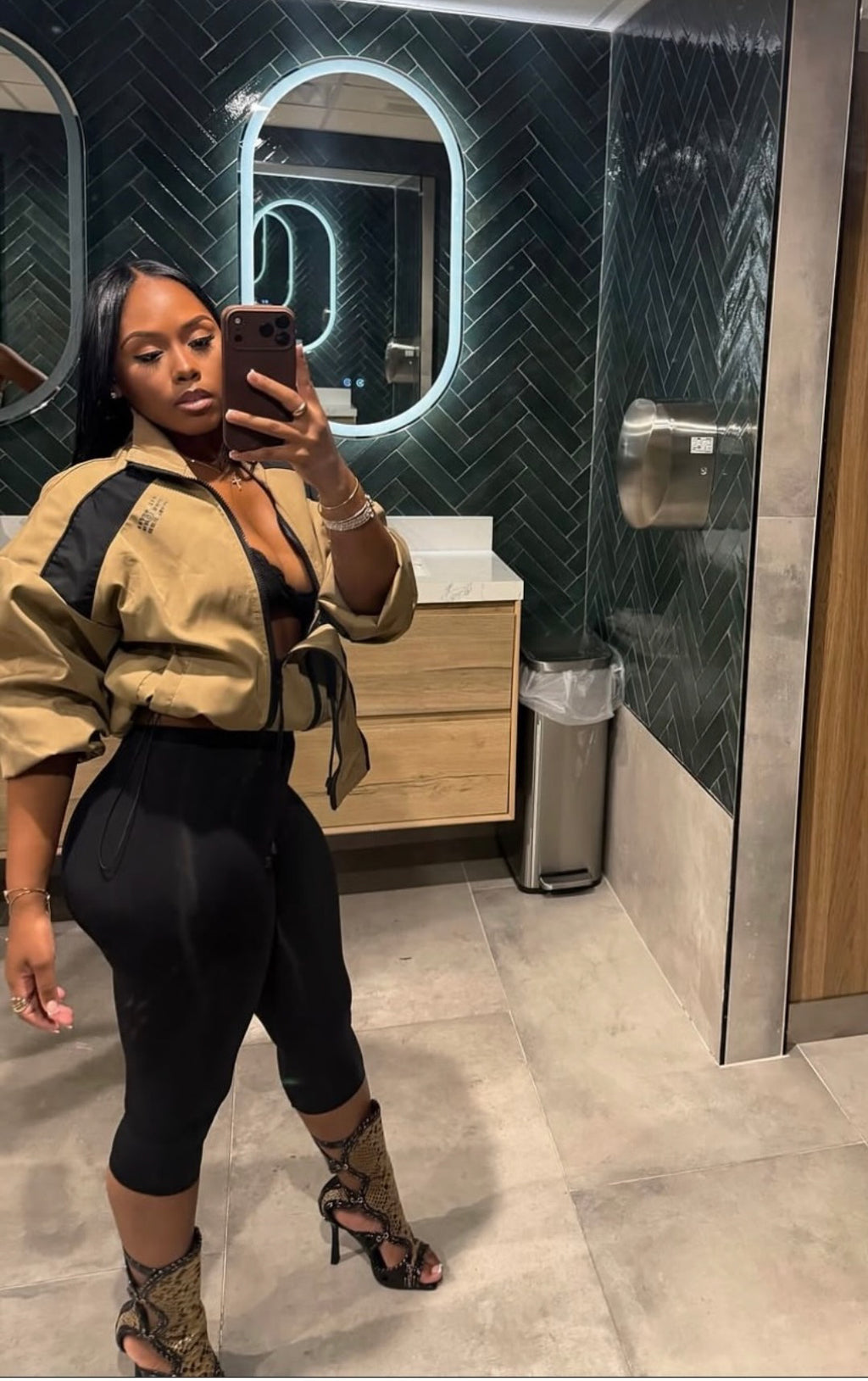 Woman wearing Demuluxe Remy Bomber Jacket, a cropped tan utility bomber with black paneling and drawstring hem 