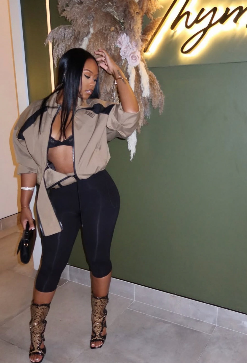 Woman wearing Demuluxe Remy Bomber Jacket, a cropped tan utility bomber with black paneling and drawstring hem 
